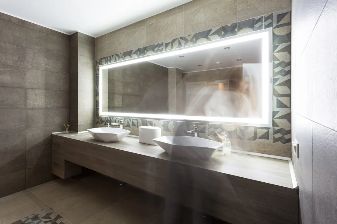 Anonymous male wearing yellow latex gloves and dark t shirt wiping mirror in bathroom with paper napkin